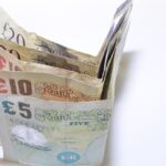 Due mani che si separano, con banconote e monete sul tavolo, simboleggiando un conto cointestato in fase di divisione.