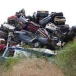 Auto in demolizione con cartelli che indicano incentivi statali per la rottamazione.